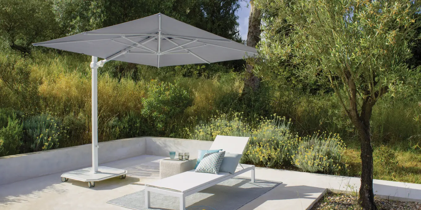 White cantilever umbrella and base with square canopy shading a sunlounger